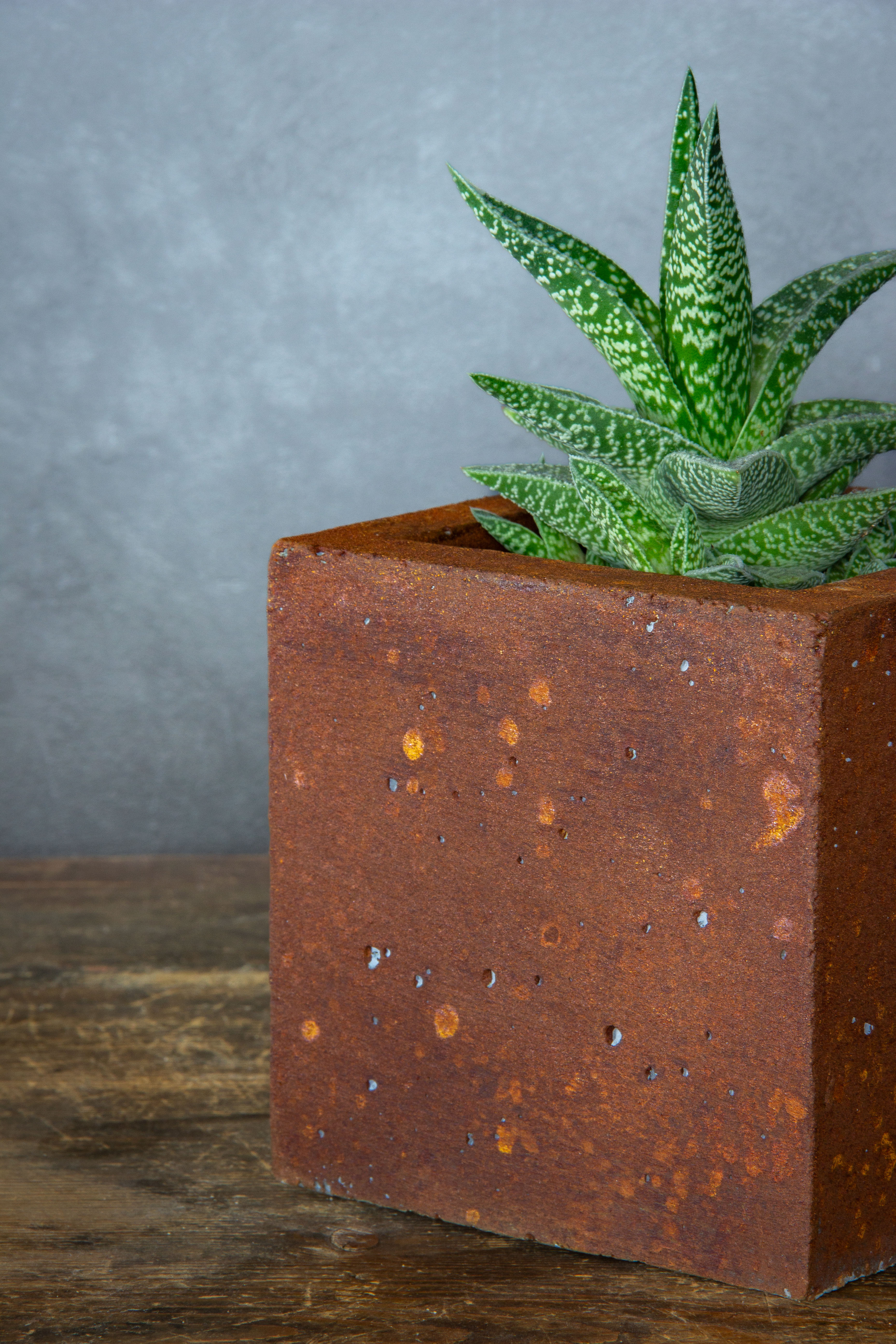 Kwadratowa betonowa osłonka z rdzawym efektem kortenu, wykonana z betonu portlandzkiego